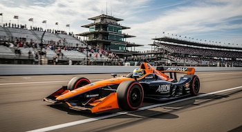 Coche de carreras naranja y negro Arrow McLaren #5 con Pato O'Ward en la pista del Indianapolis Motor Speedway. Gradas llenas y torre de control al fondo.