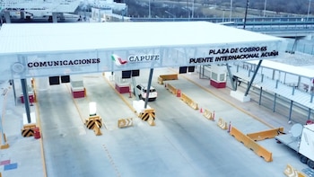 Plaza de cobro CAPUFE con varias casetas y un SUV blanco pasando. Un gran letrero blanco con los logotipos de Comunicaciones y CAPUFE atraviesa la estructura