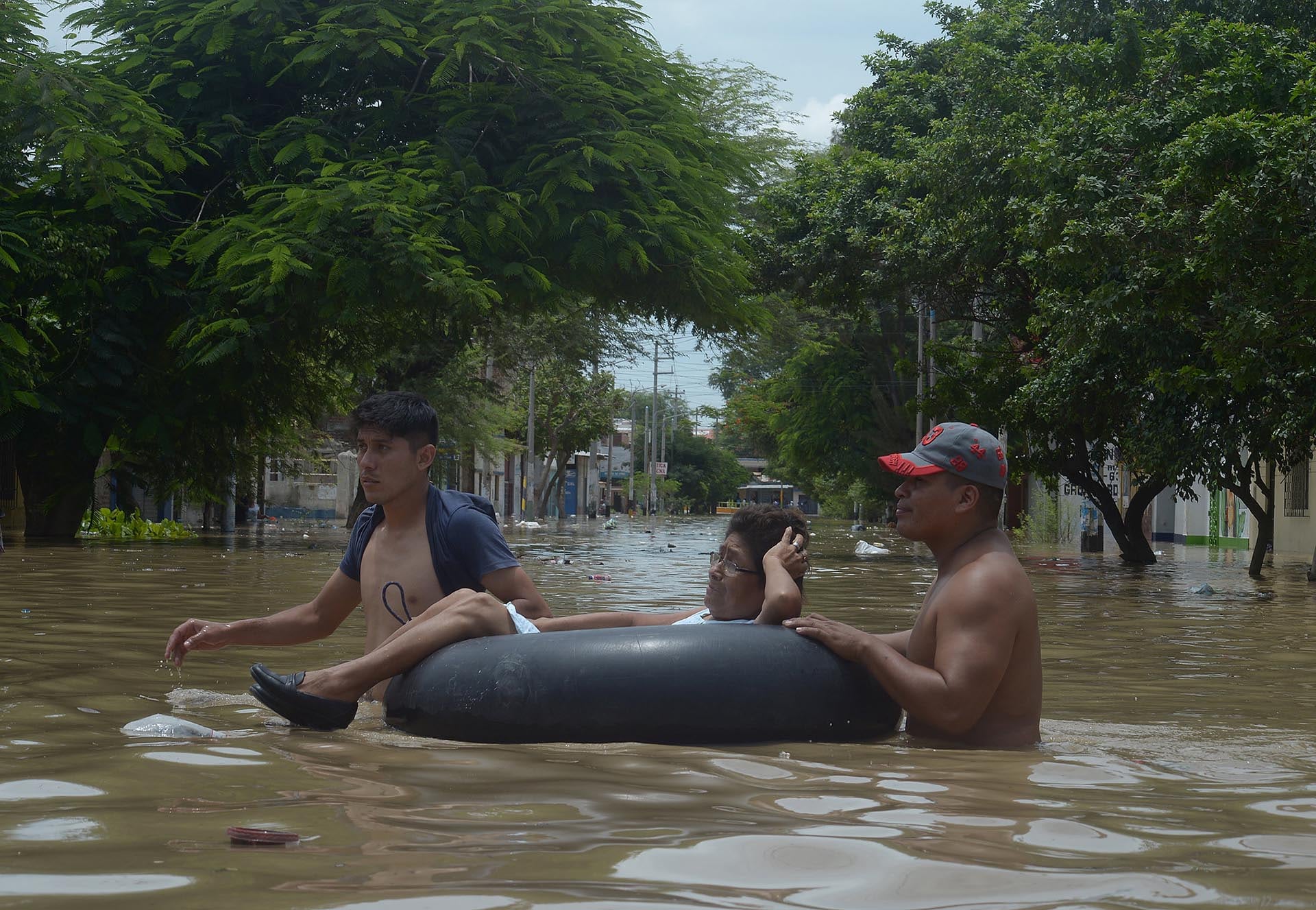 Residents help a woman cross a flooded street after rivers breached their banks due to torrential rains, causing flooding and widespread destruction in Piura, Peru, March 27, 2017. REUTERS/Miguel Arreategui EDITORIAL USE ONLY NO RESALES NO ARCHIVES