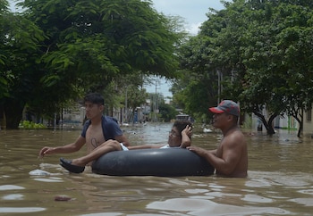Residents help a woman cross a flooded street after rivers breached their banks due to torrential rains, causing flooding and widespread destruction in Piura, Peru, March 27, 2017. REUTERS/Miguel Arreategui EDITORIAL USE ONLY NO RESALES NO ARCHIVES