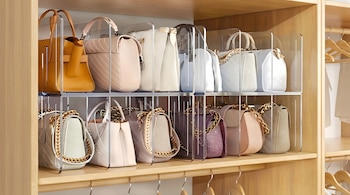 Vista detallada de dos estantes de madera con numerosos bolsos de diversos colores organizados con divisores acrílicos transparentes.