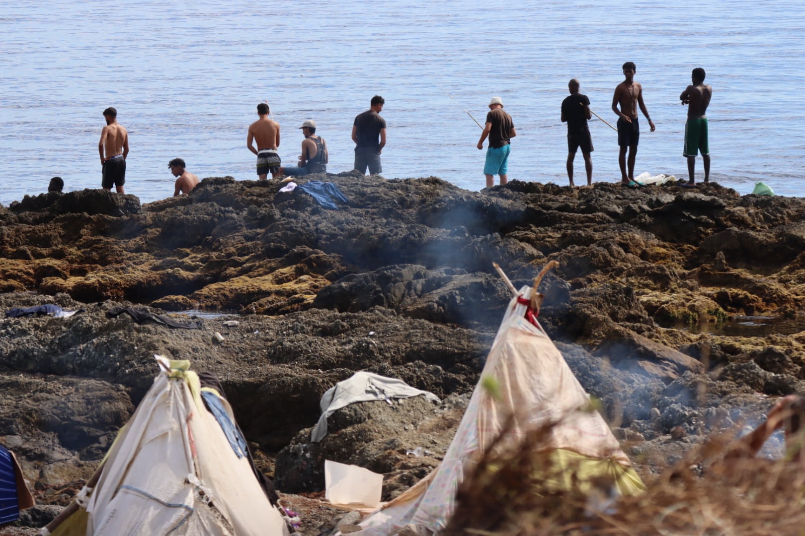 Varios migrantes en la playa de El Trampolín de Ceuta. (EFE/Reduan)