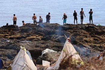 Varios migrantes en la playa de El Trampolín de Ceuta. (EFE/ Reduan)