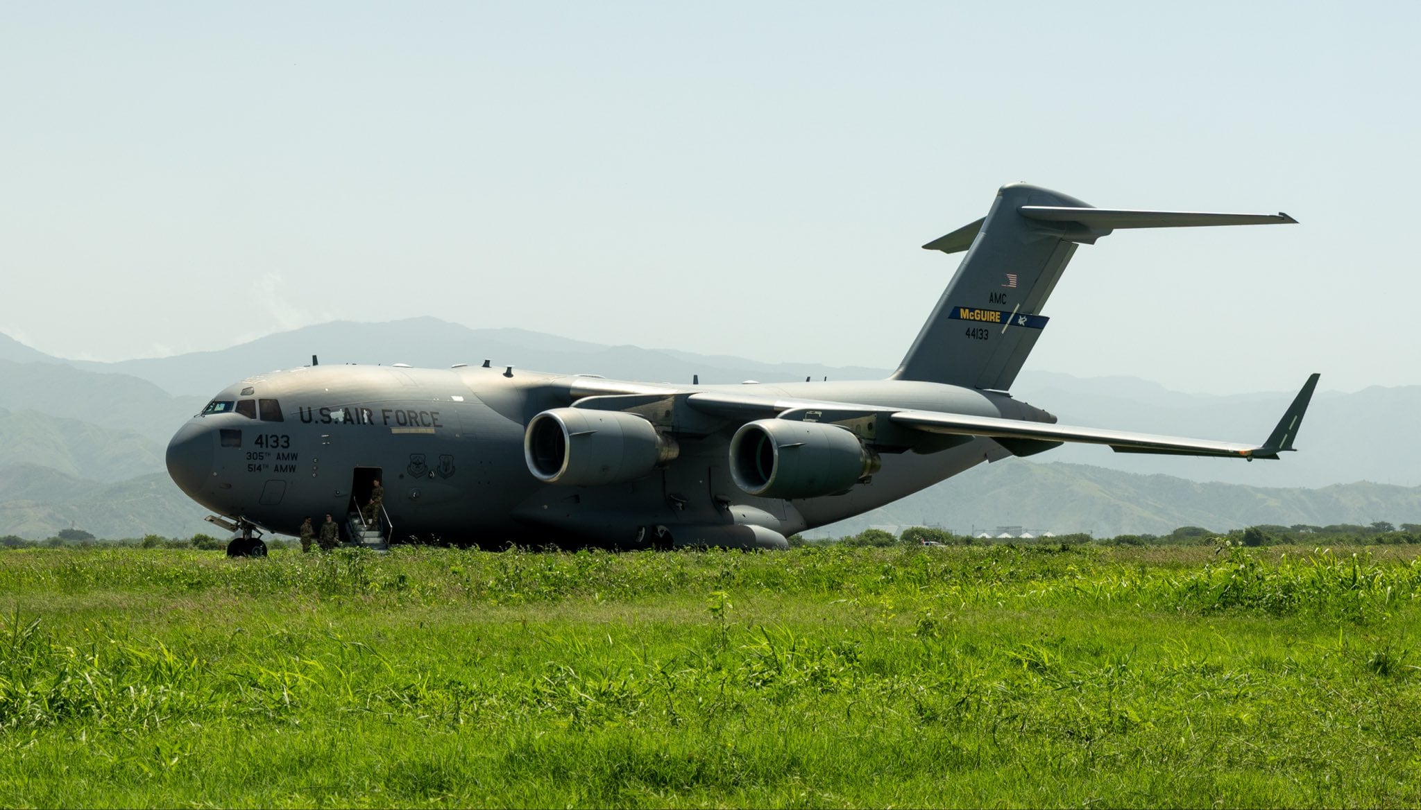 Una aeronave de transporte militar C-17 Globemaster III de la Fuerza Aérea de Estados Unidos está estacionada en un campo con montañas al fondo. (Comando Sur de Estados Unidos)