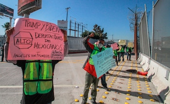 Migrantes sostienen carteles en una