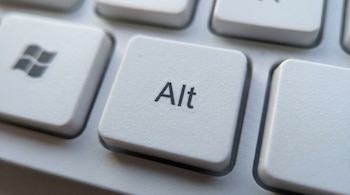 Un primer plano nítido de la tecla blanca 'Alt' de un teclado de ordenador, con el logo de Windows apenas visible a la izquierda.