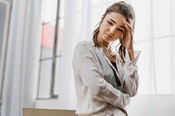 Una chica de tiro medio de pie tocándose la frente mientras mira hacia el suelo preocupada