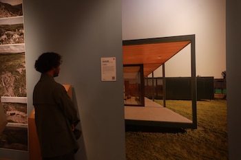 Un hombre de espaldas contempla un panel informativo y una imagen a gran escala de una vivienda de diseño moderno