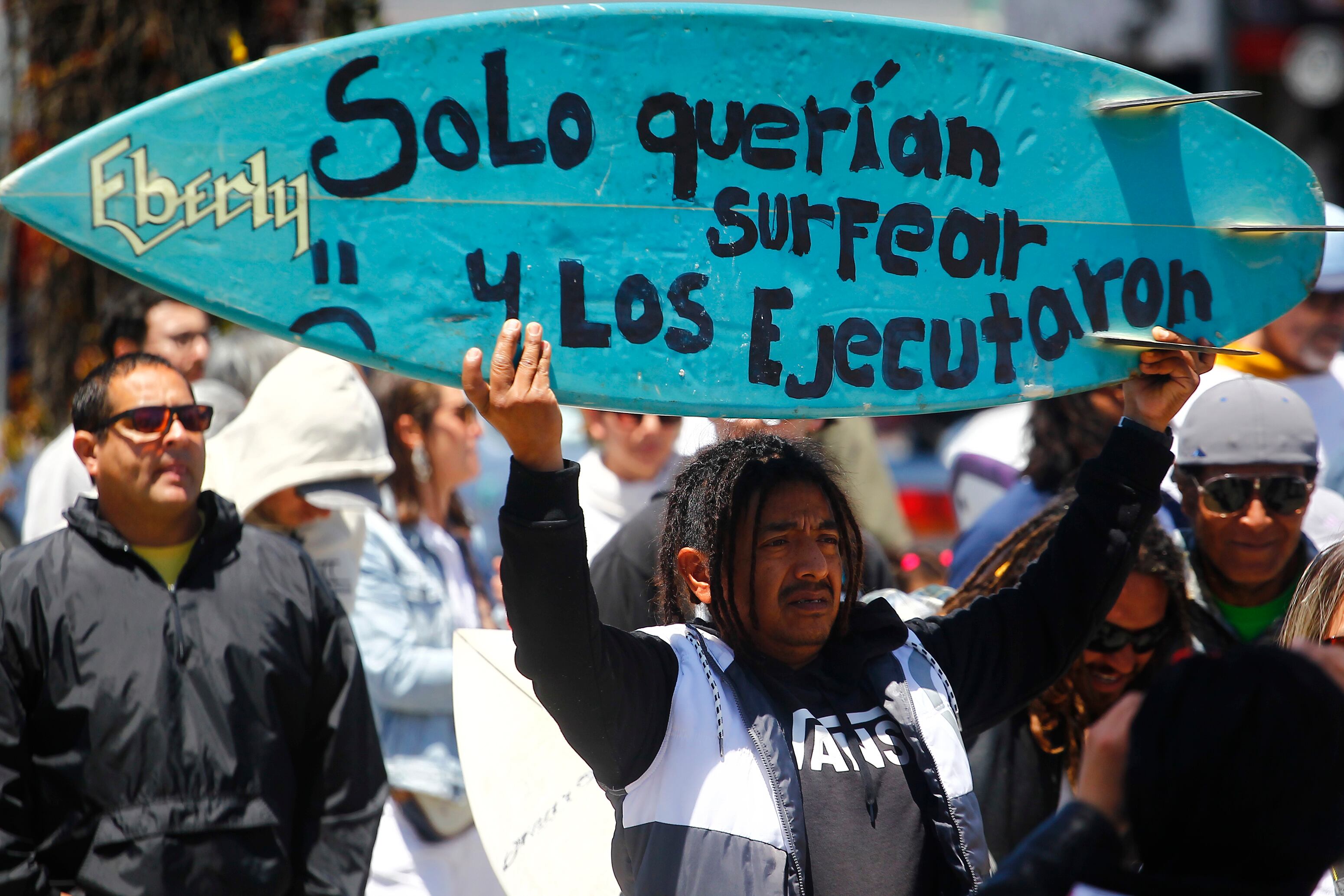 MEX6784. ENSENADA (MÉXICO), 05/05/2024.- Un hombre sostiene una tabla de surf durante una manifestación para exigir justicia por el asesinato de tres surfistas extranjeros este domingo, en la ciudad de Ensenada (México). Autoridades mexicanas señalaron este domingo que el probable homicidio de los tres surfistas extranjeros cerca de Ensenada (Baja California), en el noroeste de México, fue por el robo de un vehículo en el que viajaban y que los cuerpos presentan