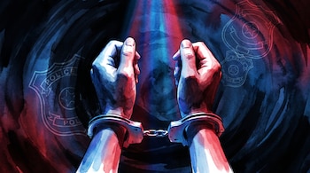 Manos esposadas levantadas al aire, iluminadas por haces de luz azul y roja, con insignias policiales transparentes en el fondo oscuro.
