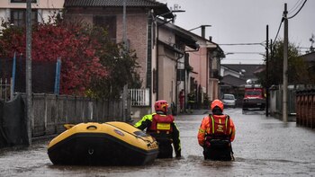 Firefighters walk across a flooded