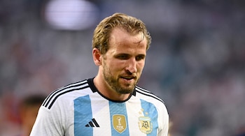 Harry Kane, hombre con barba y cabello rubio, viste camiseta de fútbol de Argentina con franjas celestes y blancas, el logo de Adidas y los escudos de AFA y FIFA.