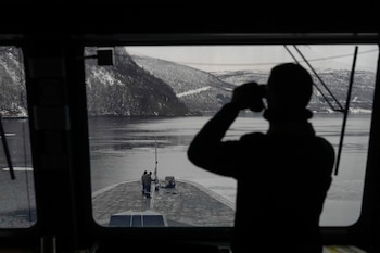 Un marino francés utiliza unos prismáticos para revisar la zona a bordo de la fragata francesa Normandie, durante una maniobra en los gélidos fiordos del norte de Noruega, el viernes 8 de marzo de 2024. (AP Foto/Thibault Camus)