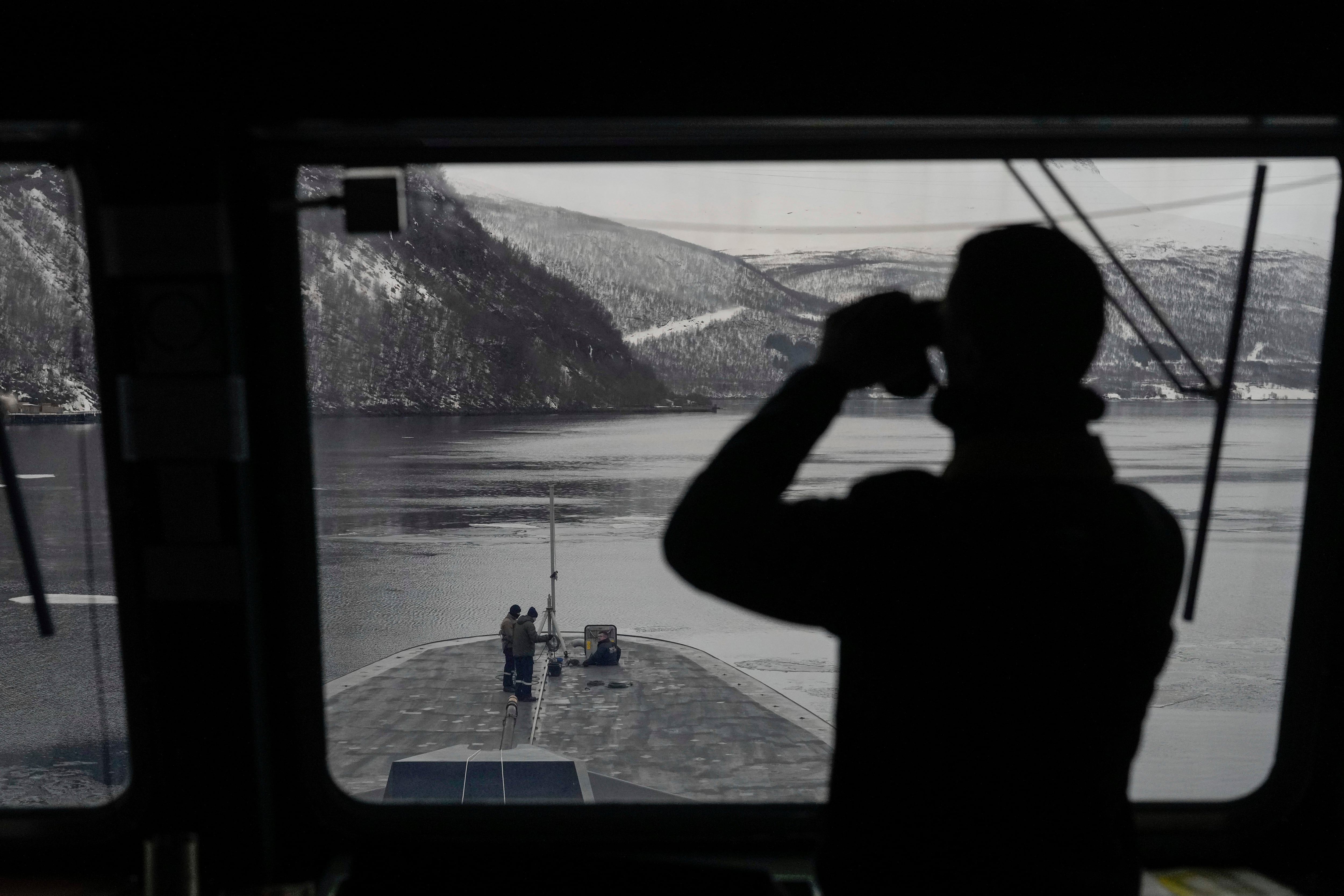 Un marino francés utiliza unos prismáticos para revisar la zona a bordo de la fragata francesa Normandie, durante una maniobra en los gélidos fiordos del norte de Noruega, el viernes 8 de marzo de 2024. (AP Foto/Thibault Camus)