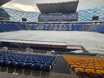 Interior del Estadio Cuauhtémoc de Puebla con el campo y parte de las gradas cubiertos por granizo blanco, asientos azules y amarillos, bajo un cielo gris