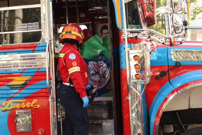 Una integrante de los Bomberos Municipales revisa la entrada de un autobús de transporte público que presenta carteles informativos sobre protocolos de salud. (Bomberos Municipales de Guatemala)