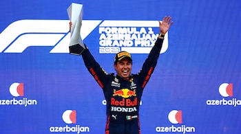 Sergio Pérez sostiene un trofeo con los brazos en alto ante un fondo azul del Gran Premio de Azerbaiyán de Fórmula 1 de 2021.