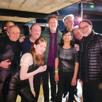 Un grupo de ocho personas posa sonriendo dentro de un recinto de espectáculos