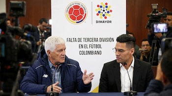 Dos hombres sentados en una mesa con micrófonos. Detrás, un cartel blanco muestra los logos de la Federación de Fútbol Colombia y DIMAYOR, con el texto sobre la falta de tercera división en el fútbol colombiano.