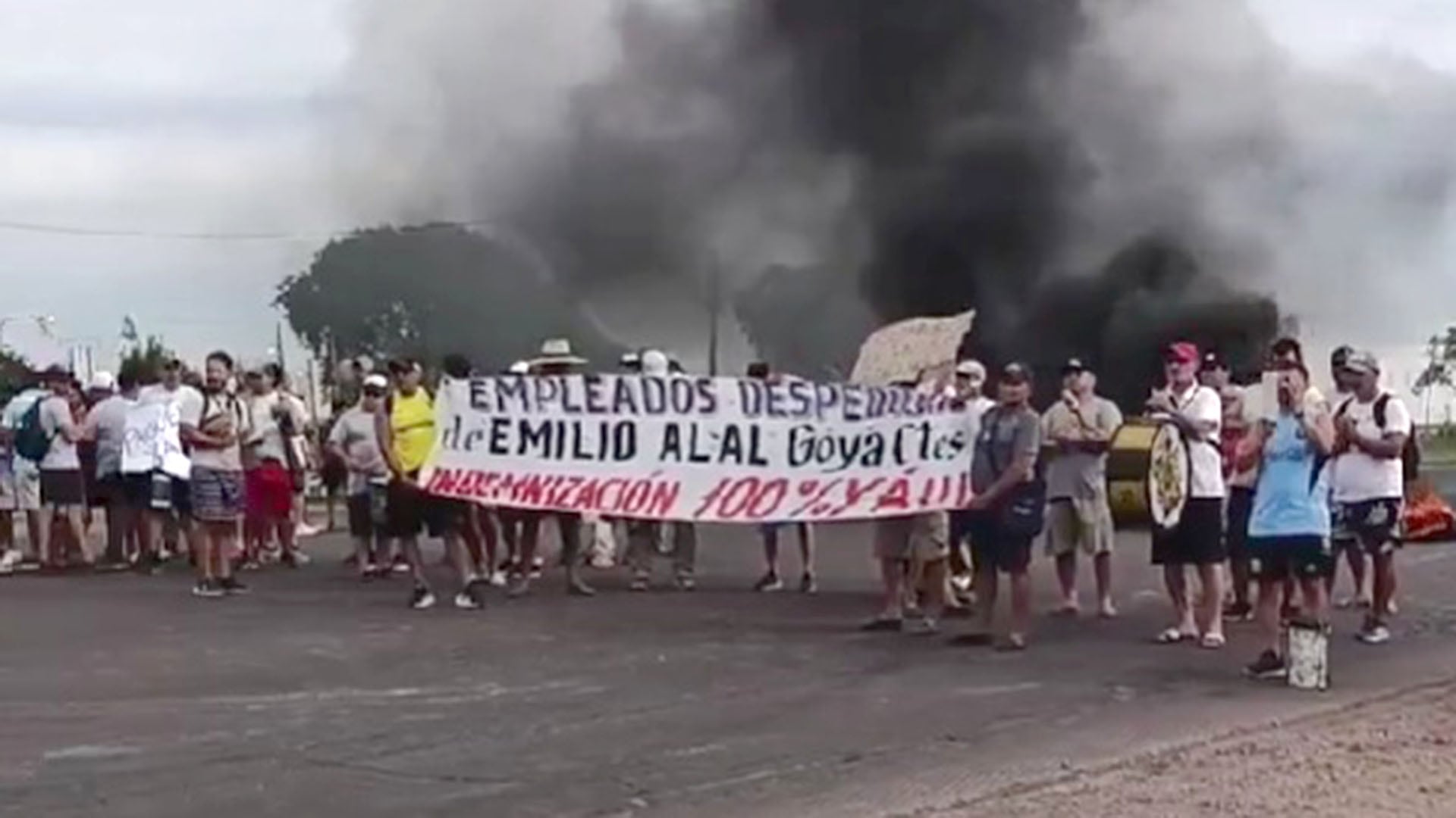 Empleados de Textil Alal en Goya se manifestaron para exigir el 100% de su indemnización, con una columna de humo negro elevándose detrás del grupo de protesta. (.)