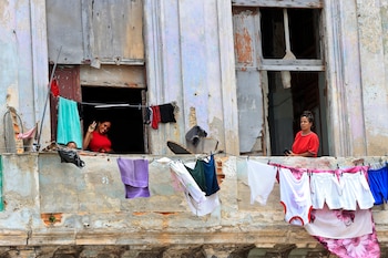 Un par de mujeres y un niño fueron captados este 12 de junio en las ventanas de un inquilinato en el centro de La Habana, luego de que el presidente de Cuba, Miguel Díaz-Canel, anunciara un paquete de reformas en el turismo, el comercio exterior, la inversión extranjera y el papel del sector privado en su país. EFE/Ernesto Mastrascusa