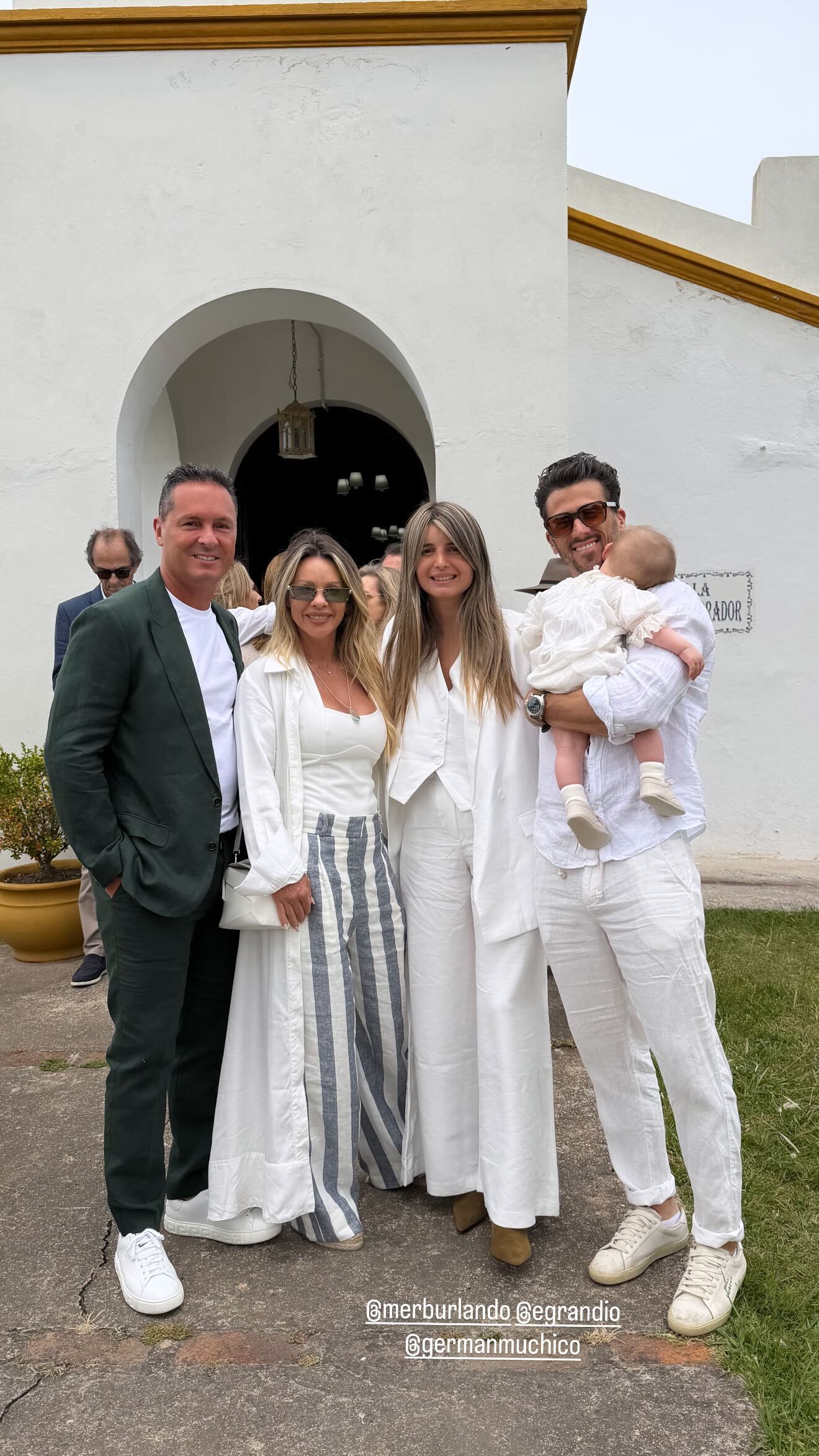 María Burlando, su pareja y amigos posan frente a la iglesia tras el bautismo de Beltrán, todos vestidos con prendas en tonos claros