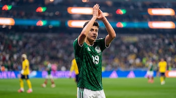Un jugador con la camiseta verde número 19 de México levanta sus manos para aplaudir en la cancha de un estadio.