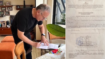 Perkins Rocha, un hombre de cabello gris y gafas, visto de perfil, firma un documento legal en una mesa de vidrio con un mantel bordado; a la derecha, un texto judicial