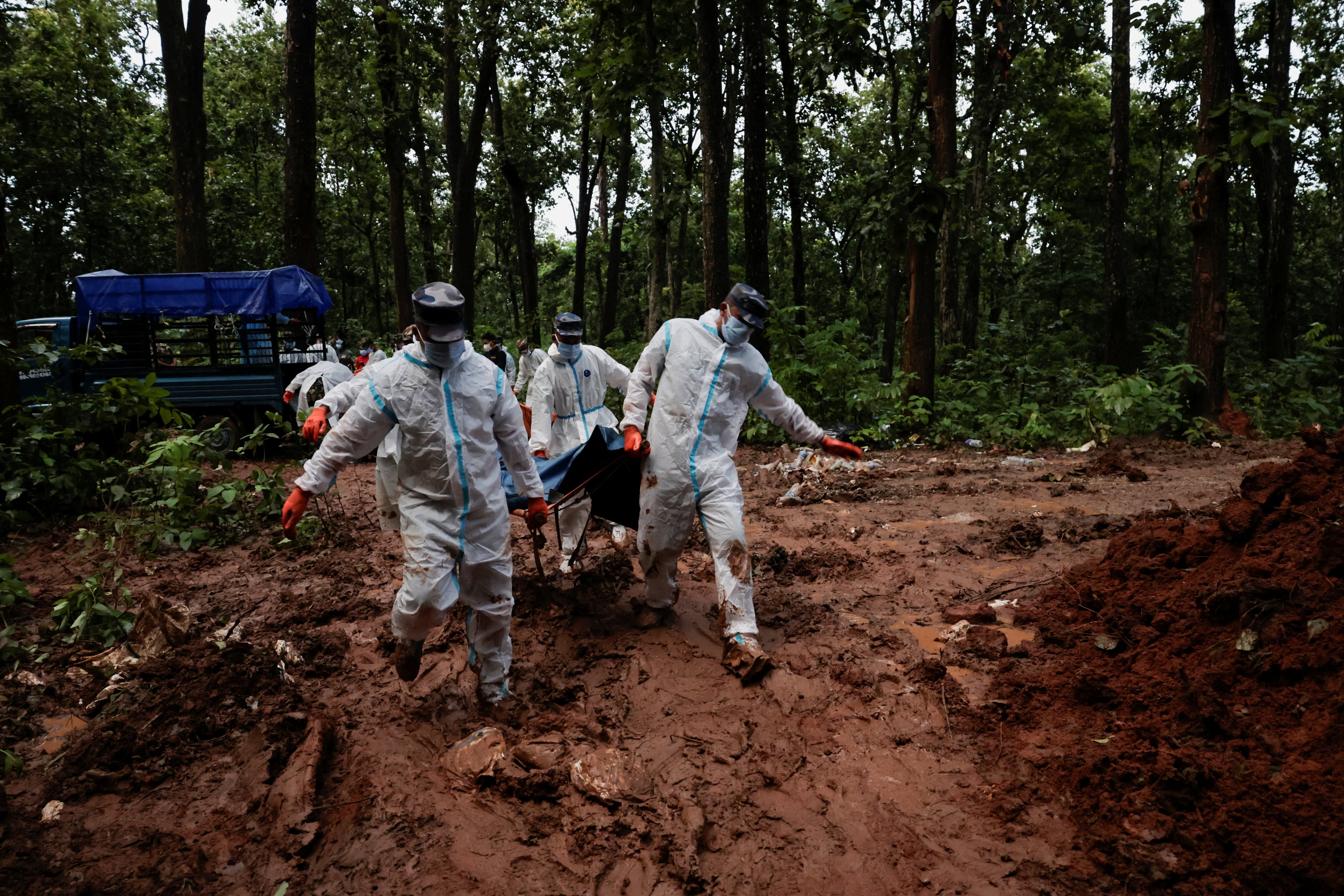 Agentes de la Fuerza de Policía Armada trabajan en el traslado de cuerpos hacia la fosa en el sitio de entierro masivo de Devghat para las víctimas de mortales inundaciones repentinas y deslizamientos de tierra en Chitwan, Nepal (Reuters)