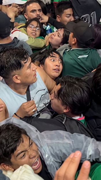 Numerosas personas apiñadas. Se ven rostros de jóvenes y adultos con expresiones de tensión y algunos con la boca abierta. Uno usa gafas