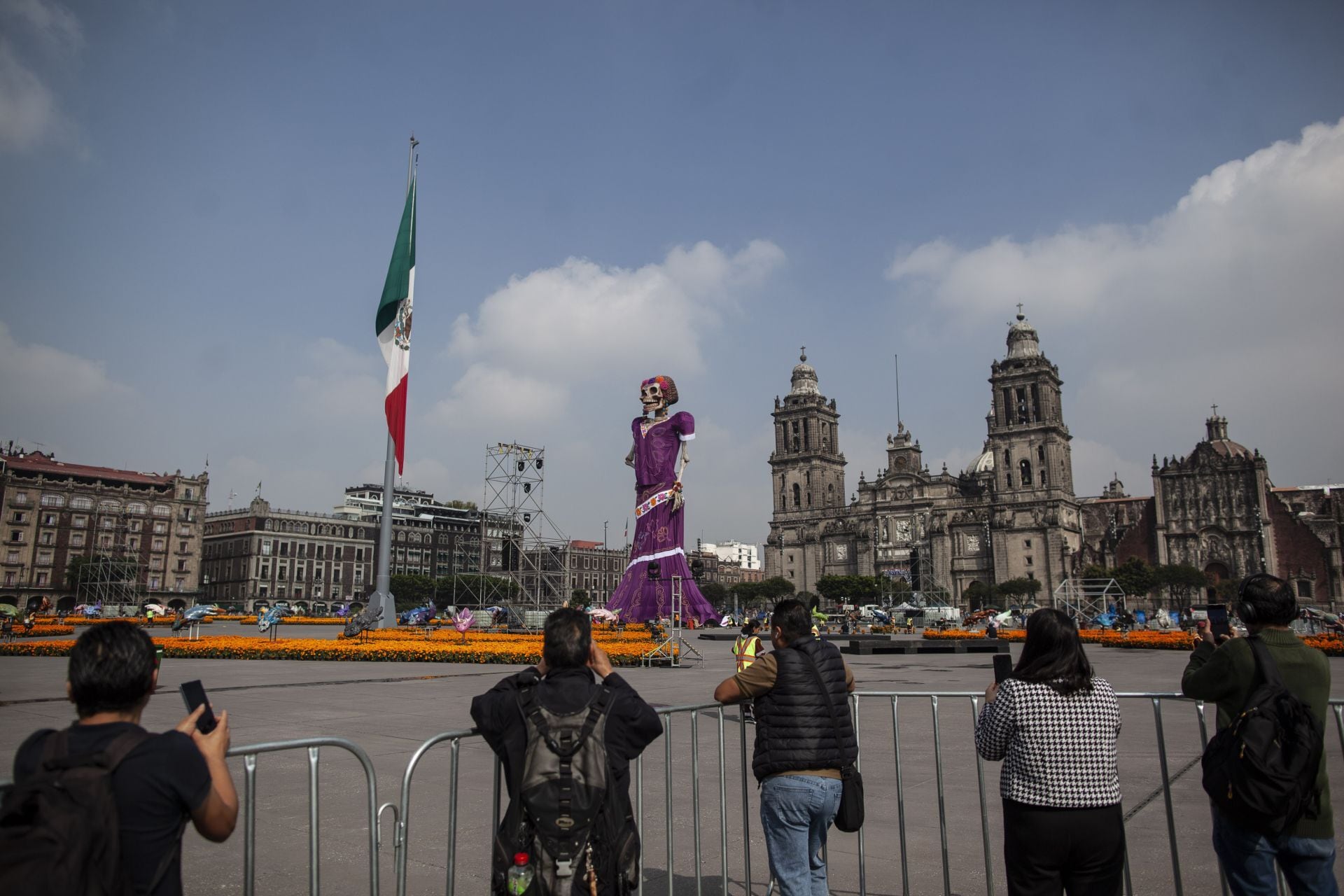 Varias personas fotografían la Catrina monumental de 32 metros instalada en el Zócalo de la Ciudad de México antes de la apertura oficial de la ofrenda. (ANDREA MURCIA /CUARTOSCURO.COM)