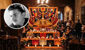 Altar de varios niveles con flores de cempasúchil, papel picado, calaveras, botellas y un retrato circular de un hombre en la esquina superior