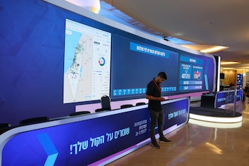 Un empleado de la Comisión Central Electoral de Israel permanece junto a una pantalla grande que muestra resultados en tiempo real (EFE/EPA/ABIR SULTAN)
