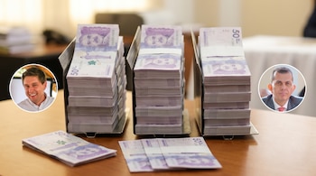 Fajos de billetes de 50.000 pesos colombianos organizados en la mesa con dos retratos circulares a los lados.