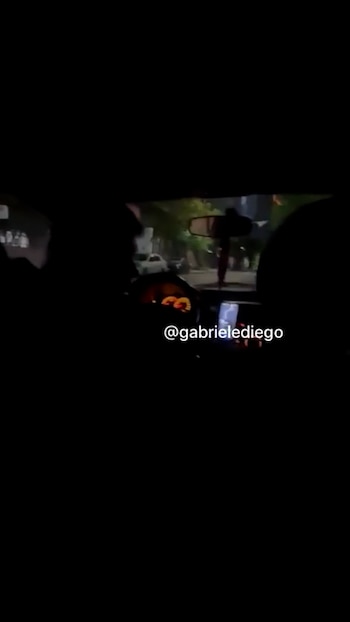 Interior oscuro de un automóvil de noche con la silueta del conductor ante el volante y la vista de la calle a través del parabrisas