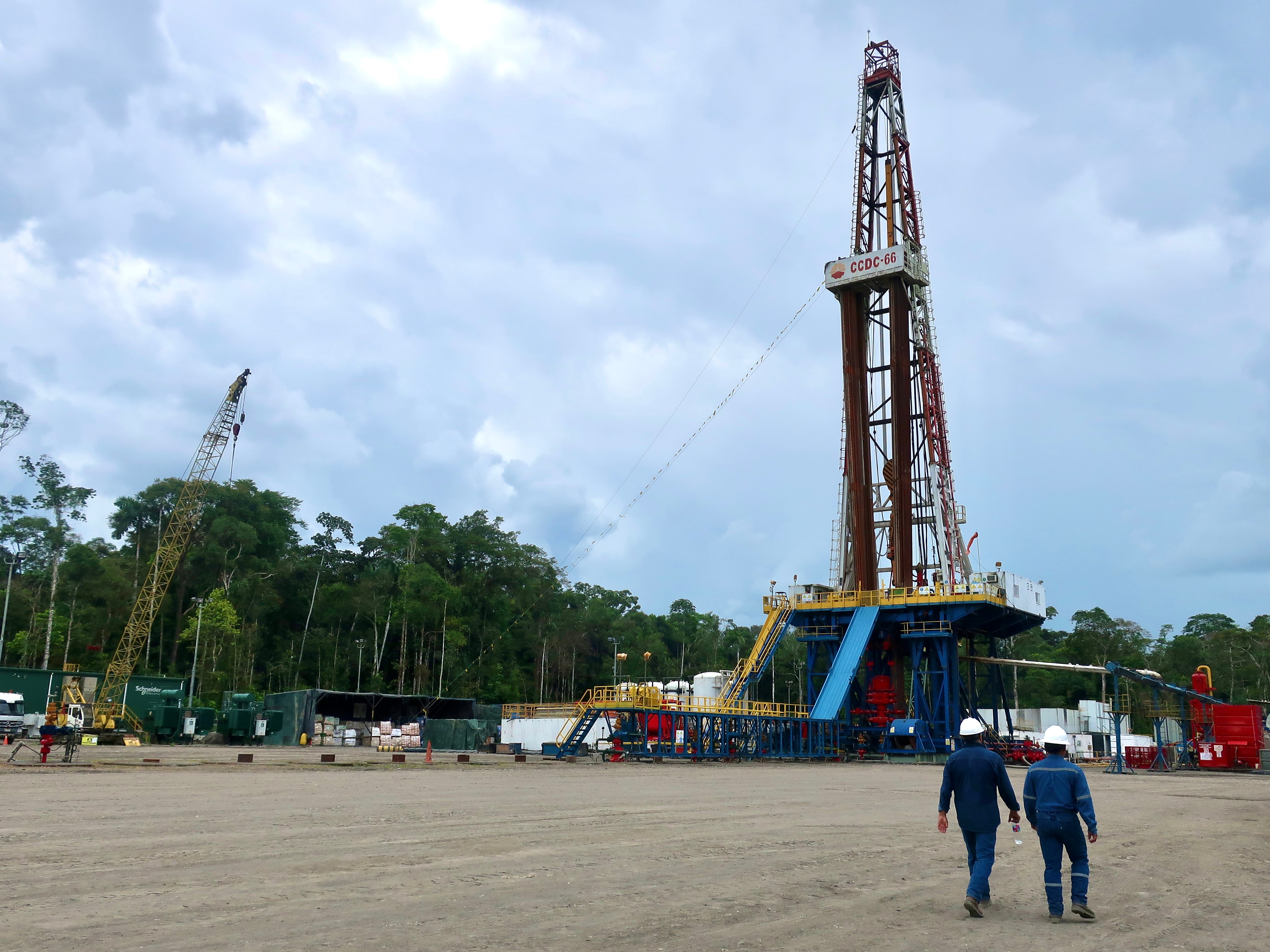 Dos operarios de la empresa estatal Petroecuador caminan frente una torre de perforación de pozos, en el Parque Nacional Yasuní (Ecuador), en una fotografía de archivo. EFE/ Fernando Gimeno