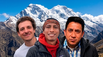 Tres hombres posan en primer plano, con el nevado Huascarán y montañas escarpadas en el fondo bajo un cielo azul con nubes dispersas.