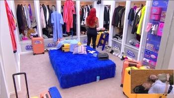 Vestidor con armarios abiertos llenos de ropa y zapatos. Mujer de espaldas con pelo rojo. Varias maletas, plataforma azul de felpa y una imagen superpuesta de dos personas