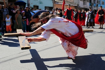 TEGUCIGALPA (HONDURAS). Una persona simula la caída de Jesús durante el recorrido del viacrucis de Semana Santa este viernes, en Tegucigalpa (Honduras). EFE/ Gustavo Amador