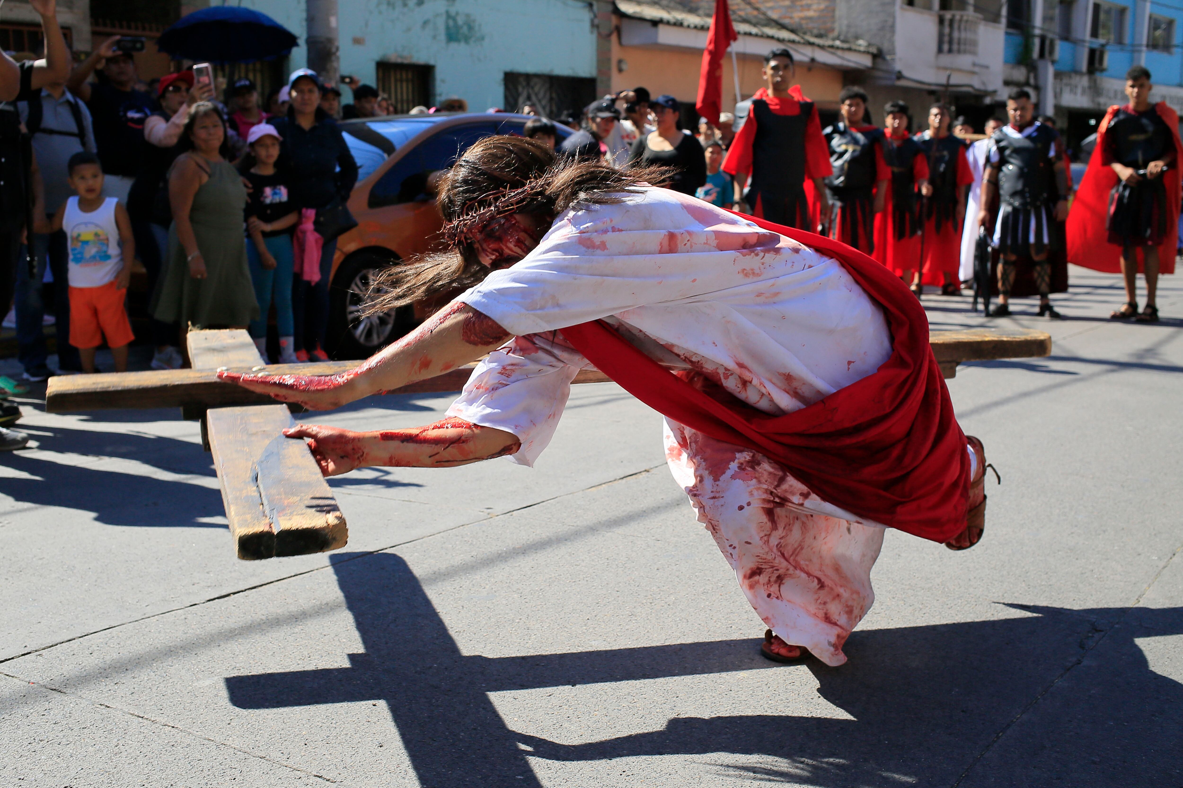 TEGUCIGALPA (HONDURAS). Una persona simula la caída de Jesús durante el recorrido del viacrucis de Semana Santa este viernes, en Tegucigalpa (Honduras). EFE/ Gustavo Amador