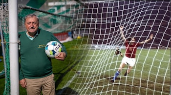 Hombre mayor con bigote y suéter verde sujeta un balón de fútbol junto a un poste. A su derecha, arquero con camiseta roja y brazos alzados detrás de la red.