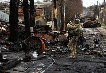 Un militar usa su teléfono móvil para filmar un tanque y vehículos blindados rusos destruidos en Bucha (REUTERS/Zohra Bensemra)