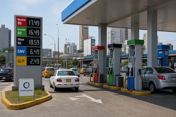 Panel electrónico con listas de precios junto a surtidores, automóviles en espera y un cartel con el logotipo de Osinergmin.