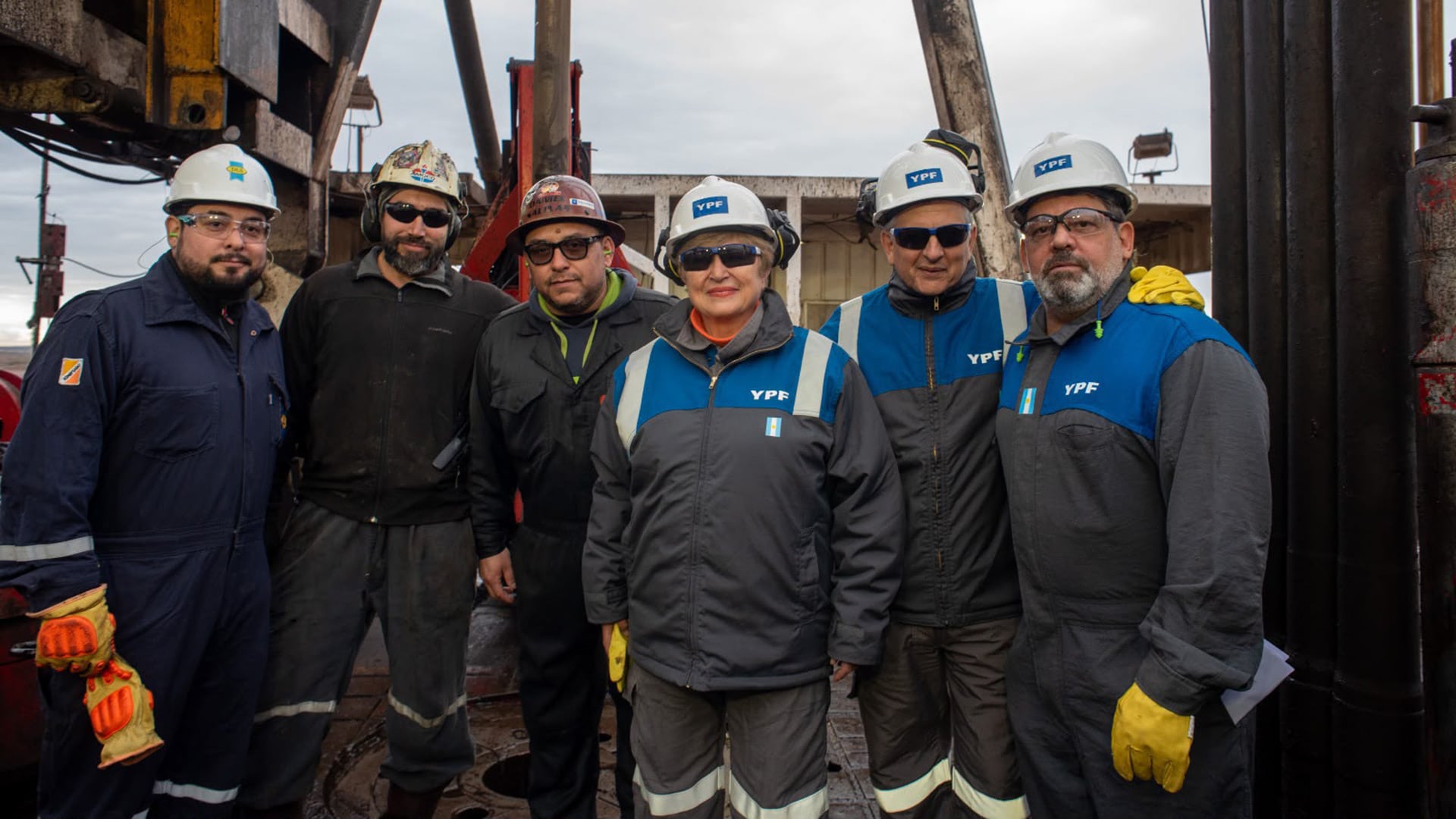 Un equipo de seis trabajadores de YPF posa en el área de explotación de Vaca Muerta, Argentina.