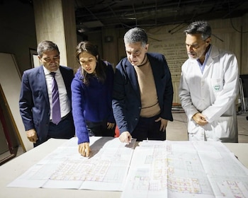 Cuatro personas, incluyendo a Jorge Macri y Fernán Quirós, se inclinan sobre una mesa grande para revisar planos arquitectónicos detallados en un interior