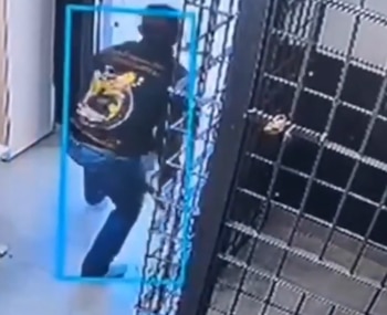 Un hombre viste chaqueta oscura y pantalones vaqueros mientras corre junto a unas rejas metálicas