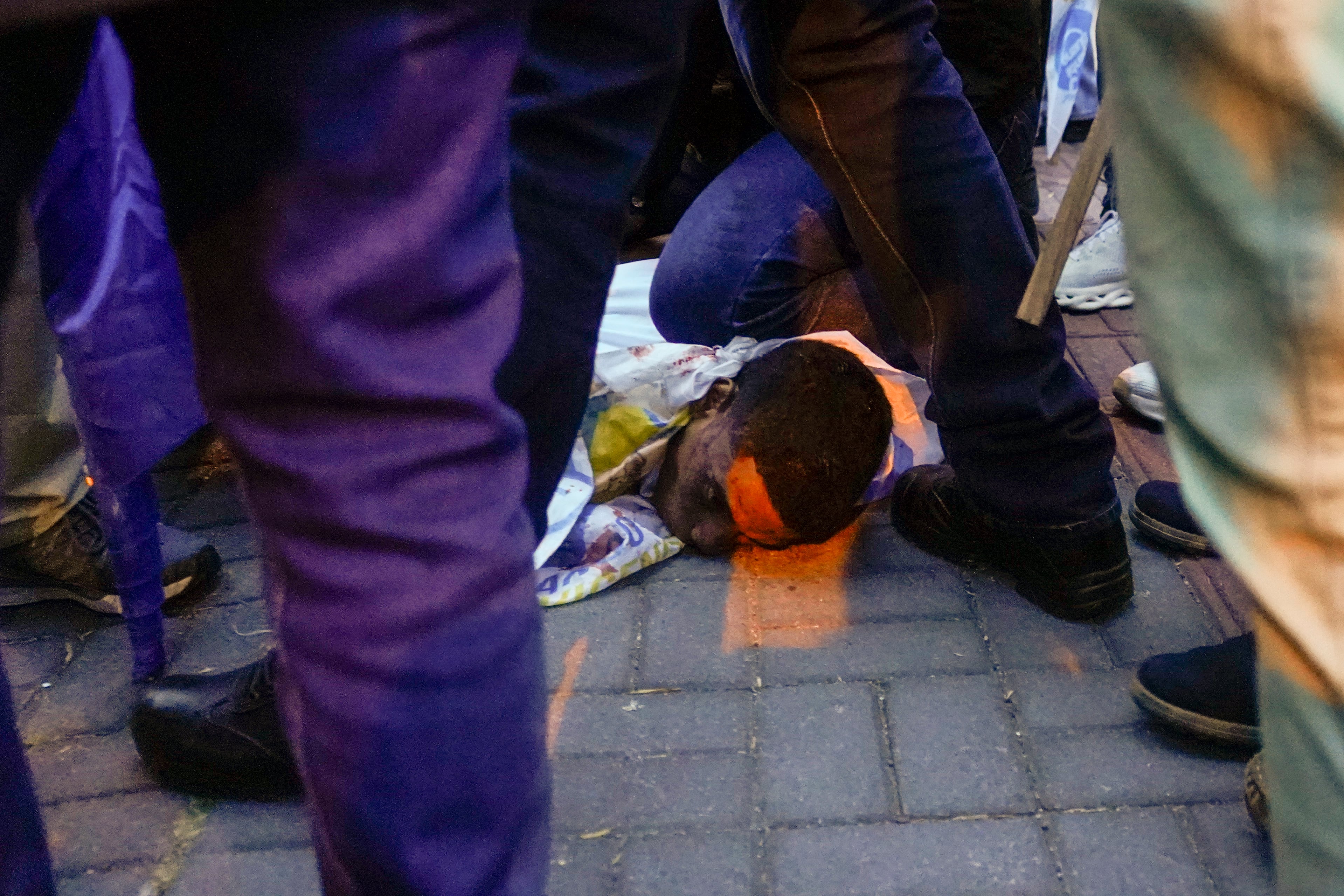 Una persona herida en el suelo tras el ataque a tiros en el que el candidato presidencial Fernando Villavicencio fue asesinado a la salida de un mítin electoral en un colegio en Quito, Ecuador, el miércoles 9 de agosto de 2023. (AP Foto/Juan Diego Montenegro)