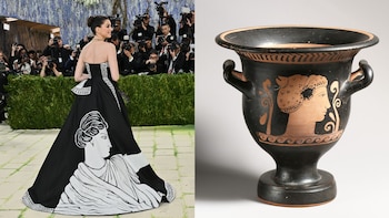 Anne Hathaway posa con un vestido blanco y negro con el perfil de una mujer clásica, junto a un crátera griega con un diseño similar