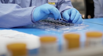 A staff member wearing a protective suit prepares a kit of Ellume's first over-the-counter coronavirus disease (COVID-19) antigen test, which can be used at home, in this still image taken from an undated video, in Brisbane, Australia. Ellume/Handout via REUTERS NO RESALES. NO ARCHIVES THIS IMAGE HAS BEEN SUPPLIED BY A THIRD PARTY. MANDATORY CREDIT