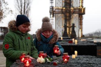 Unos niños colocan velas mientras visitan un monumento a las víctimas del Holodomor durante una ceremonia conmemorativa con motivo del 87.º aniversario de la hambruna de 1932-1933, en la que murieron de hambre millones de personas, en Kiev (Ucrania), el 28 de noviembre de 2020. REUTERS/Valentyn Ogirenko (REUTERS/Valentyn Ogirenko/Archivo)